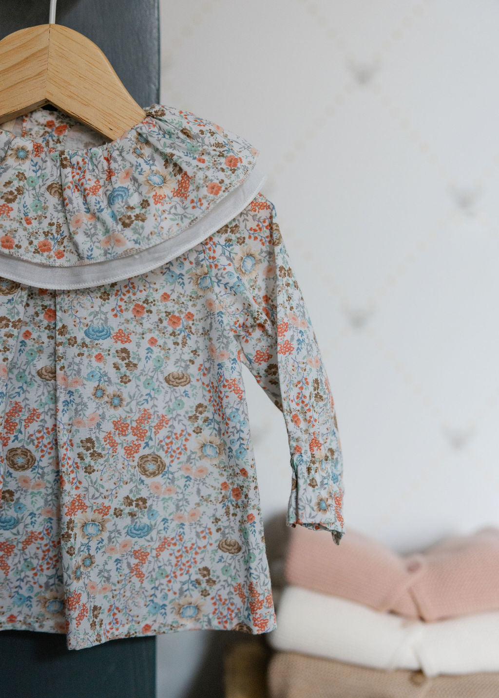 Floral blouse on a hanger against a neutral background