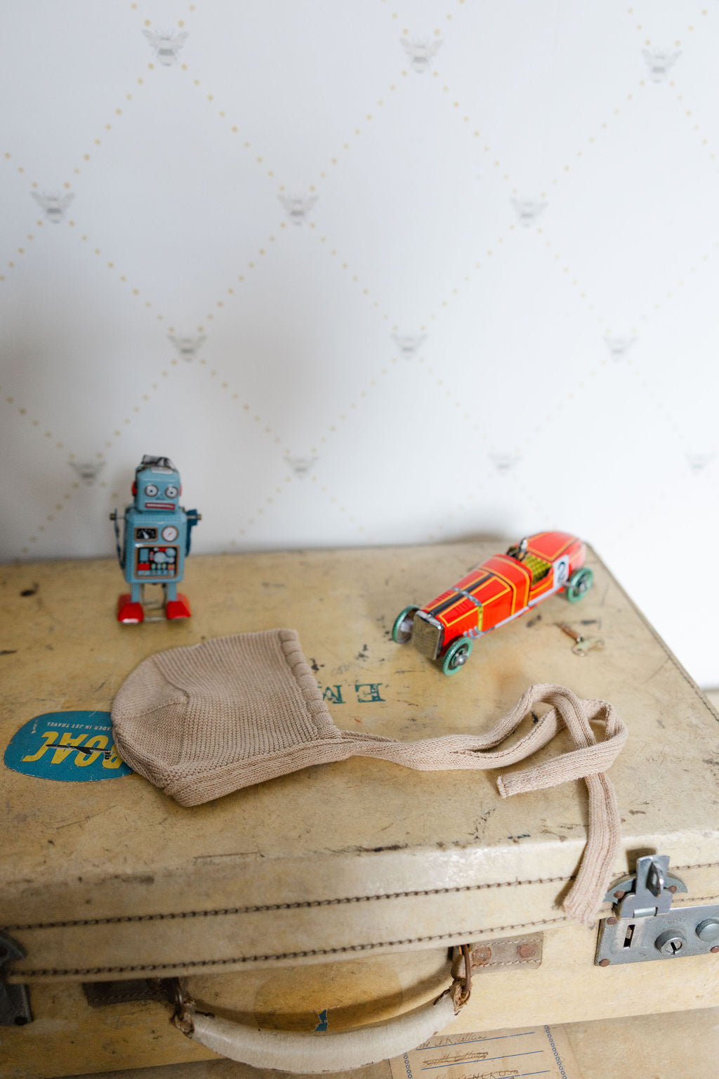 Vintage suitcase with a robot, car, and beige bonnet with  textured white backgrounding 