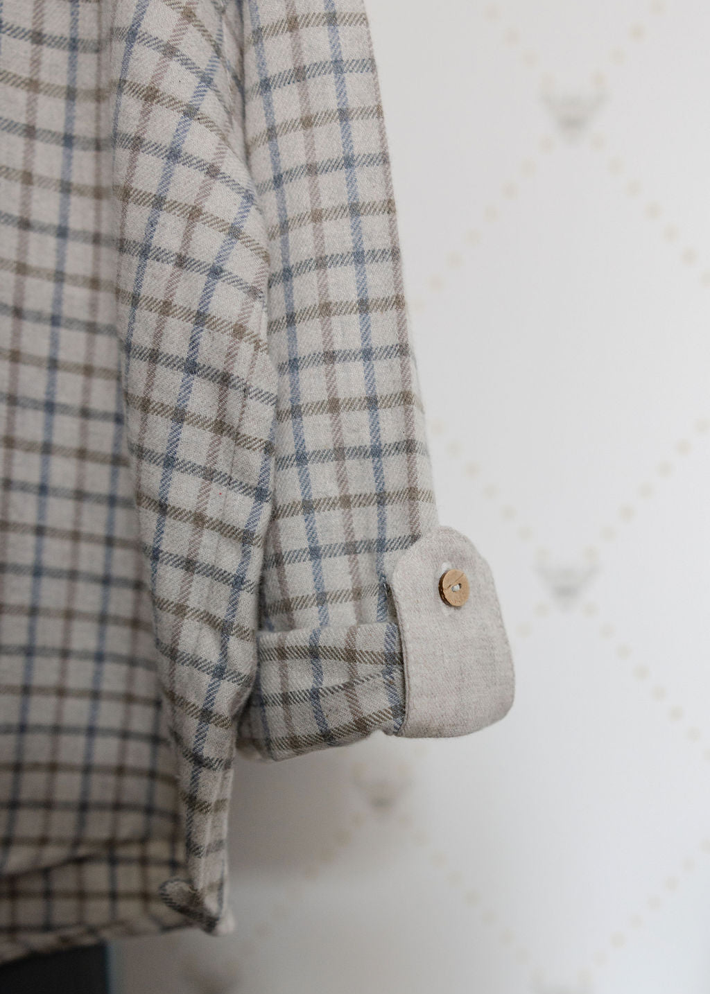 Close-up of a plaid shirt with a button on a textured white background