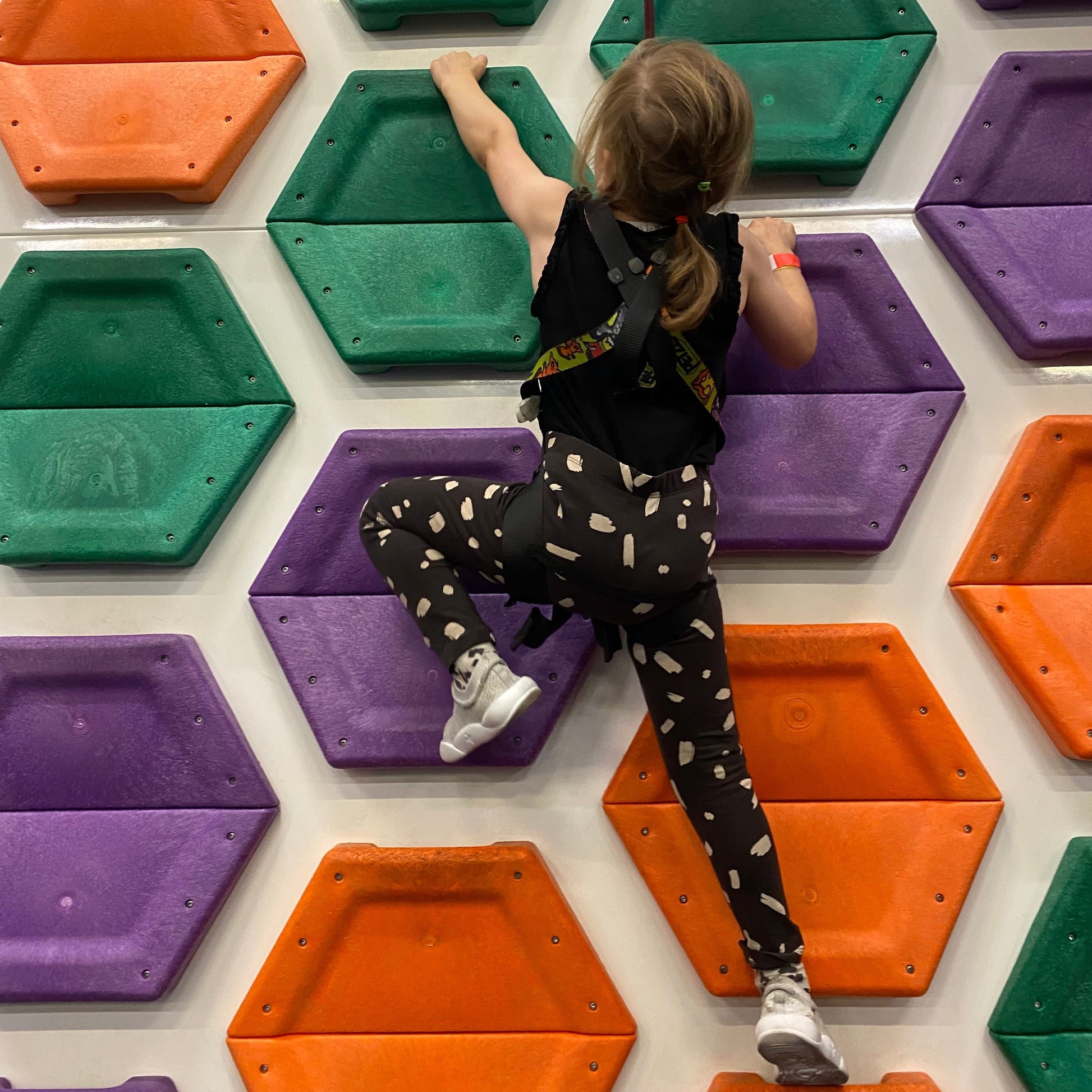 Girl on climbing wall with Grey Dubs Flex wide-fit sensory-friendly kids trainer
