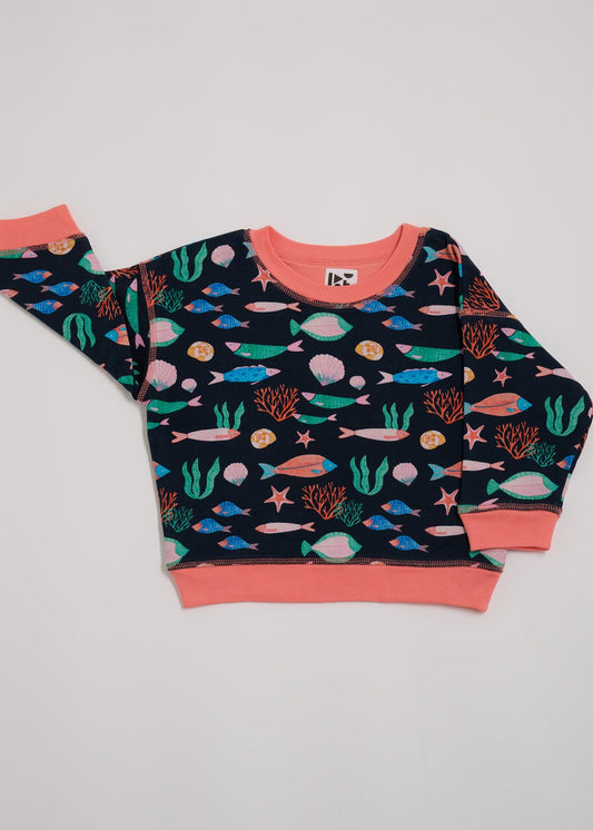 Front of sweatshirt featuring an all over vibrant navy fish print with contrast coral neck and sleeve trim.