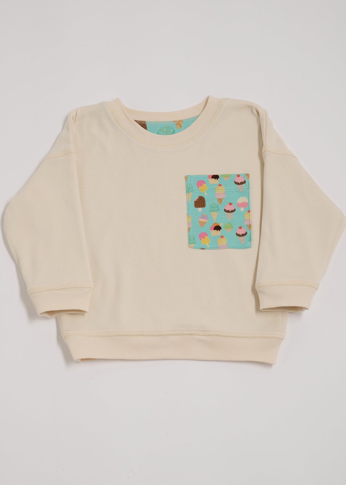 Front of ecru sweatshirt with oversized turquoise ice cream print chest pocket.