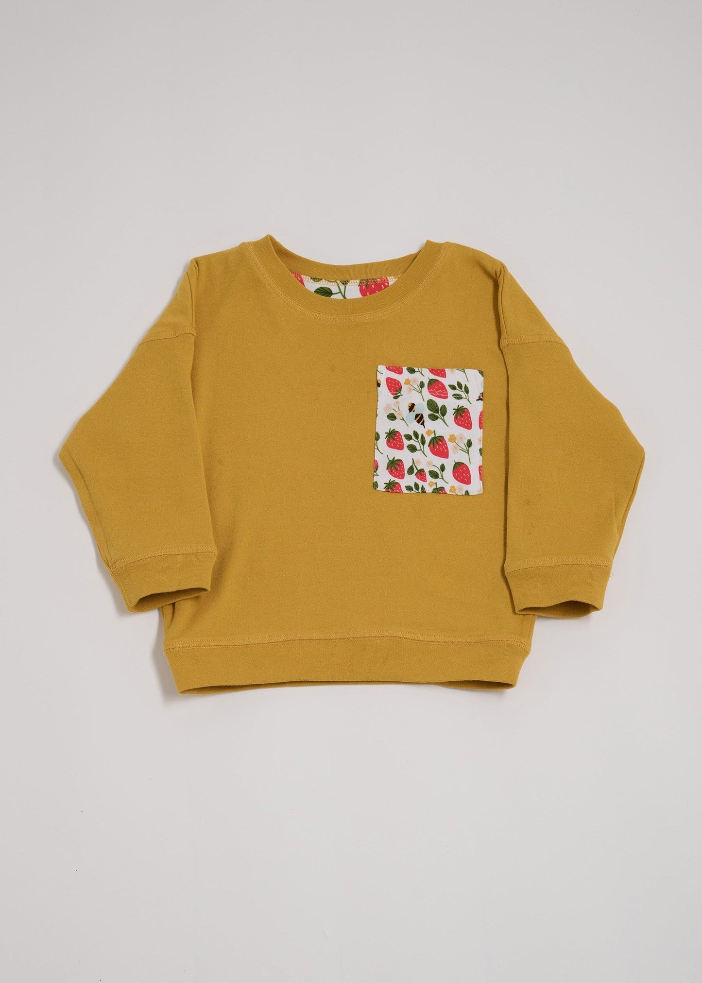 Front of honey coloured sweatshirt featuring oversized strawberry and bees chest pocket.