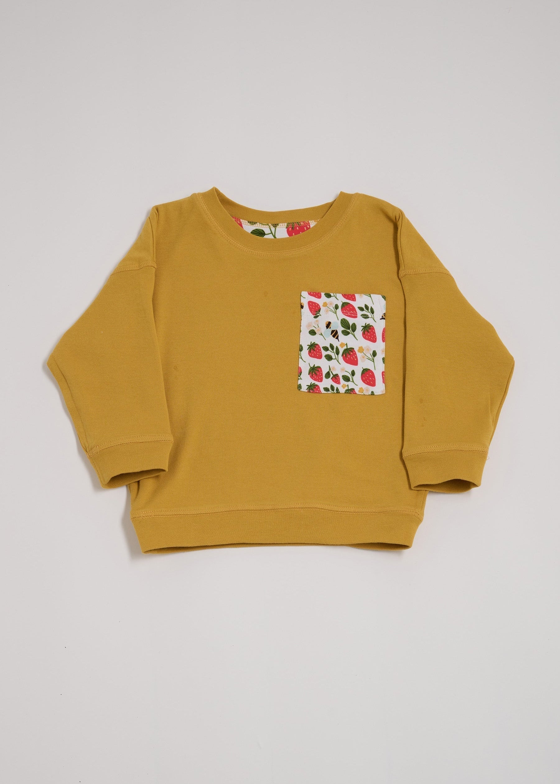 Front of honey coloured sweatshirt featuring oversized strawberry and bees chest pocket.