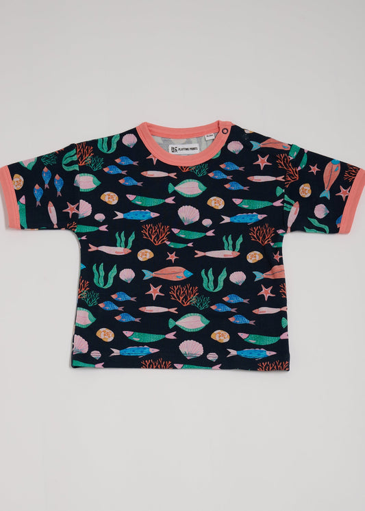 Front of short sleeved t-shirt featuring an all over vibrant navy fish print, with contrast coral neck and sleeve trim and neck poppers.