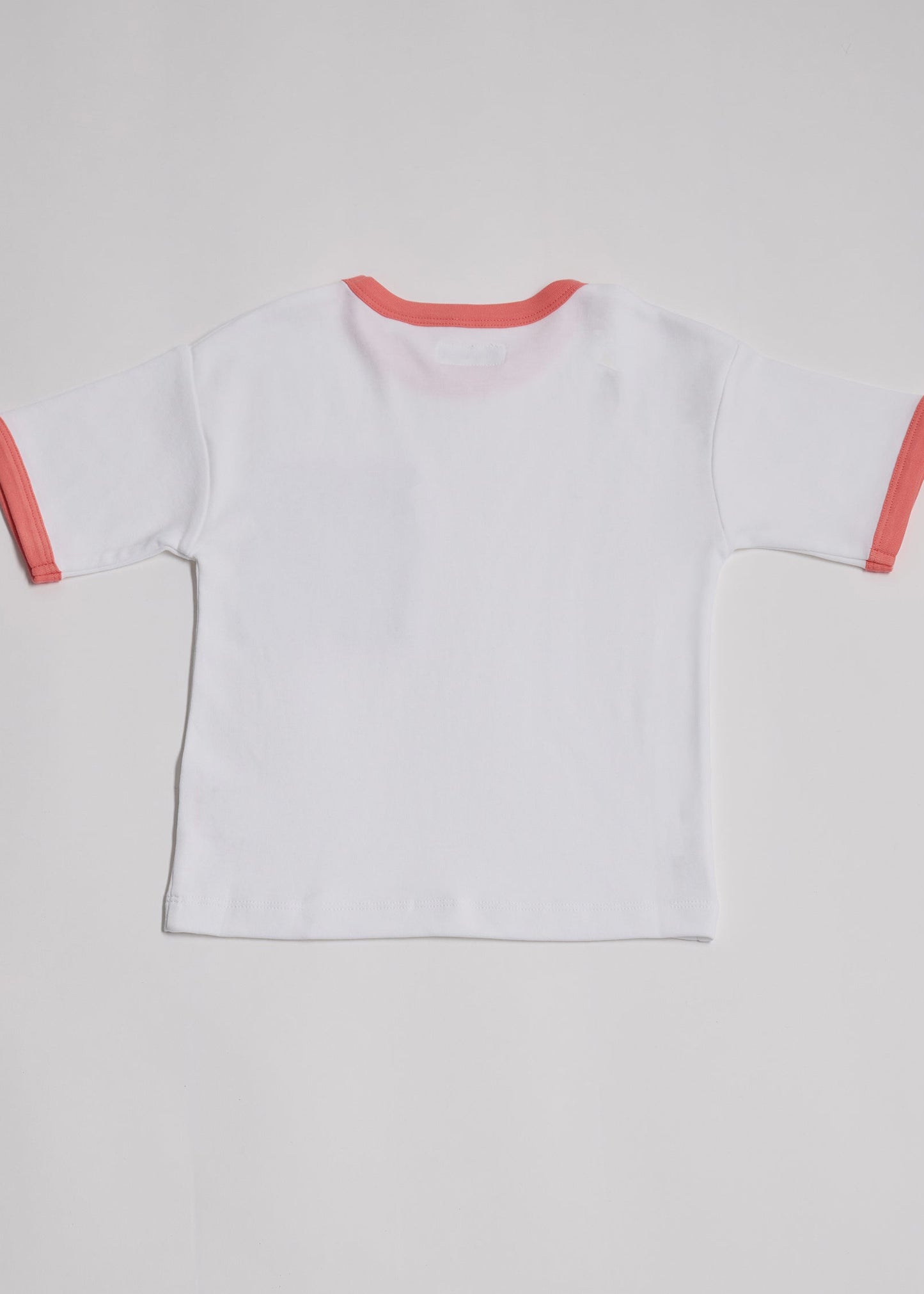Back of white short sleeved t-shirt with coral neck and sleeve trim.