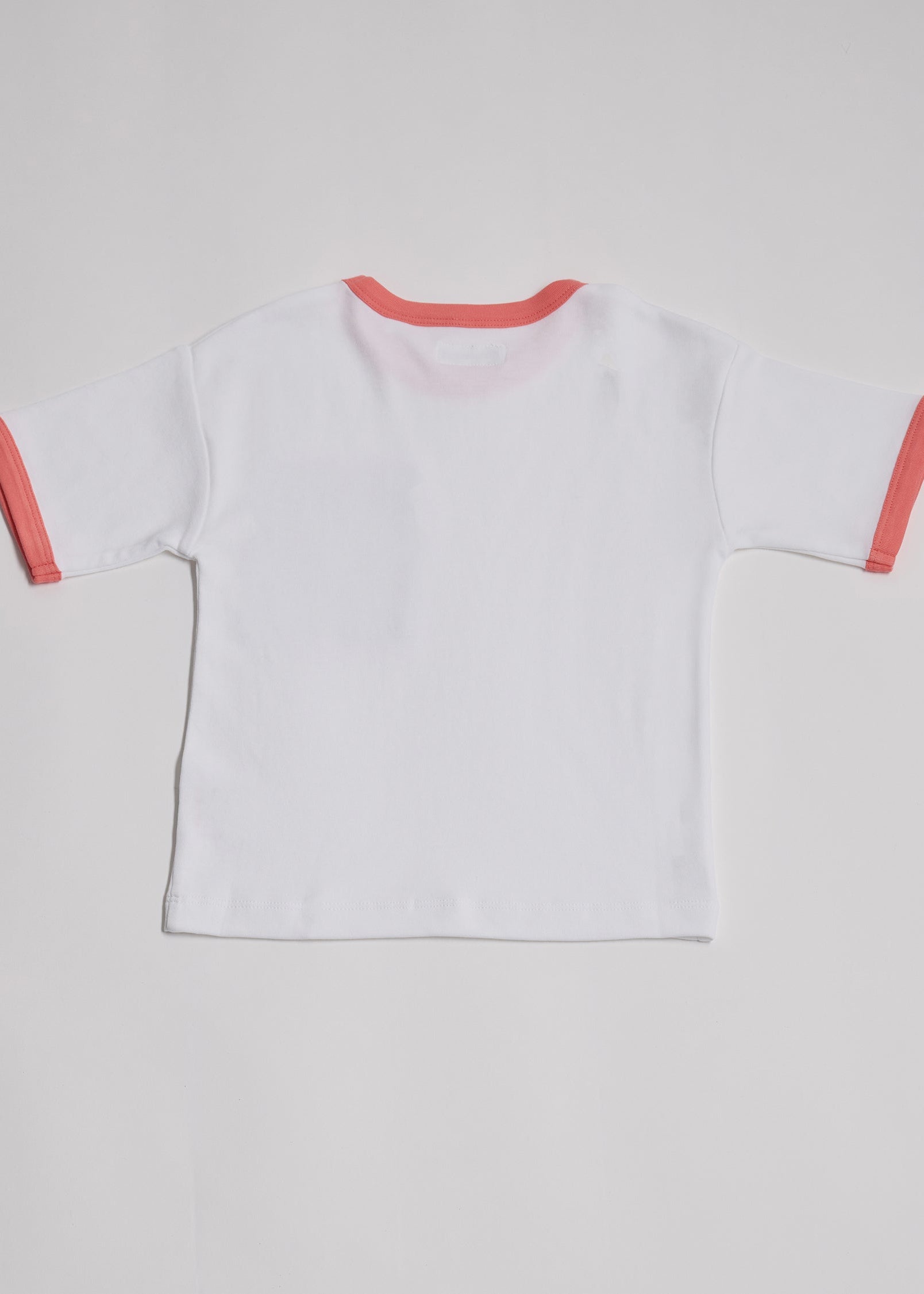 Back of white short sleeved t-shirt with coral neck and sleeve trim.