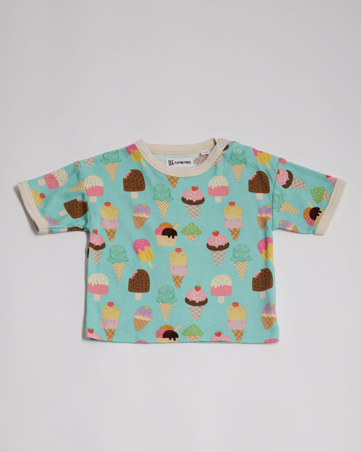 Front of short sleeved t-shirt featuring an all over turquoise ice cream print, contrast ecru neck and sleeve trim and neck poppers.