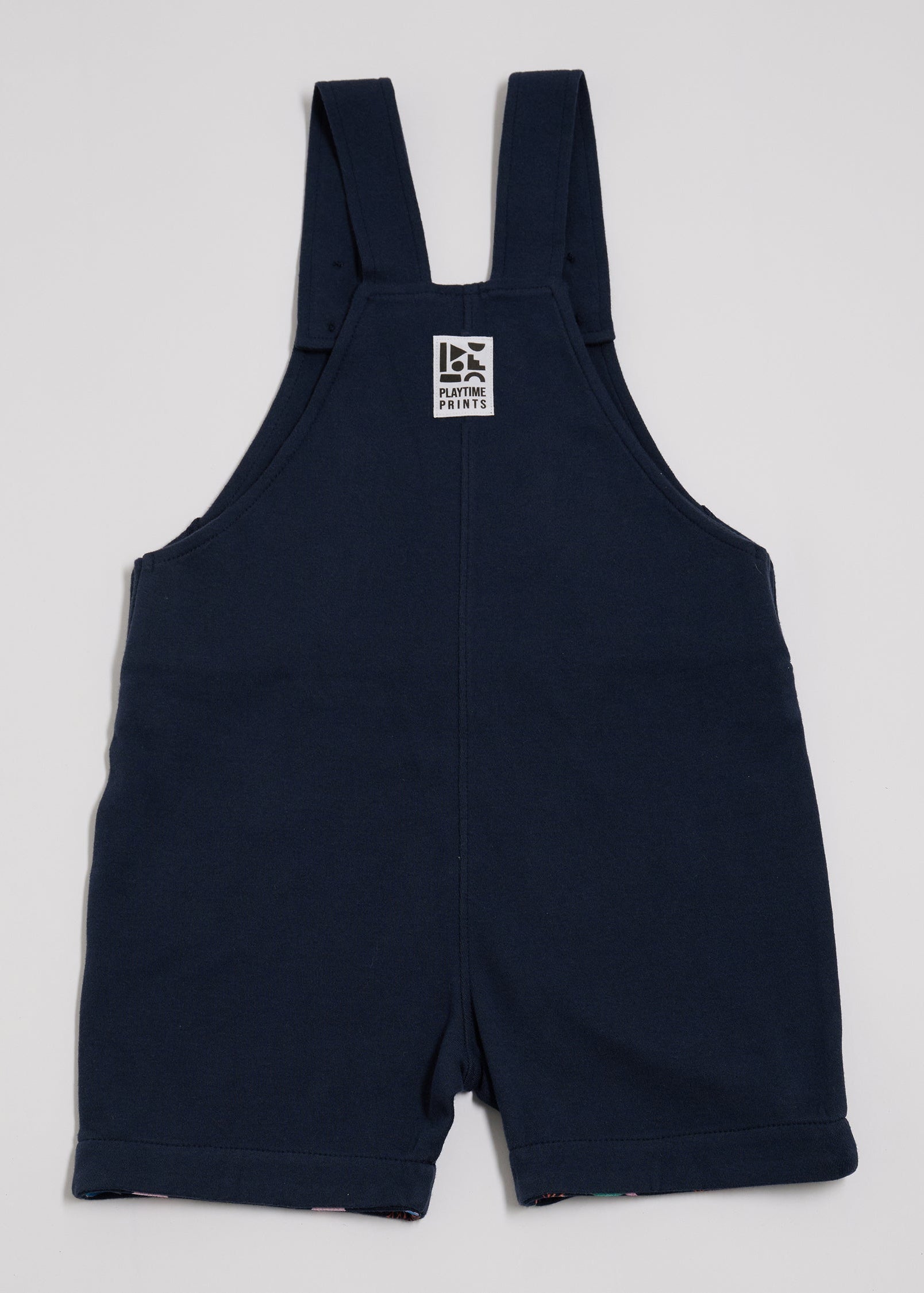 Back of navy short dungarees with Playtime Prints brand label.