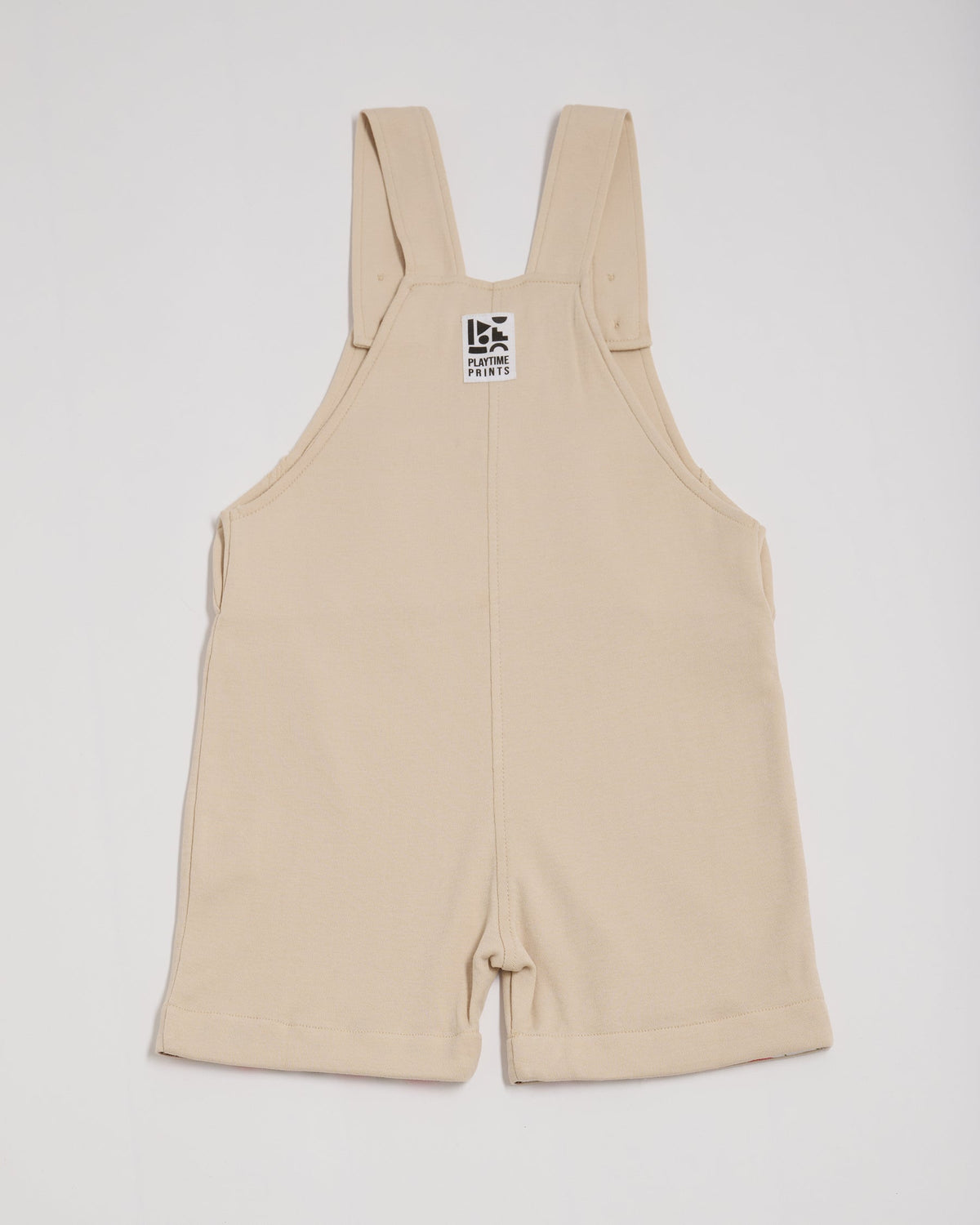 Back of beige short dungarees with Playtime Prints brand label.