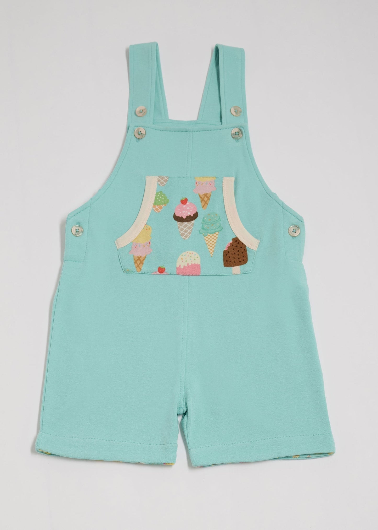 Front of turquoise short dungarees with bright ice cream print pocket, vanilla buttons and vanilla trim.