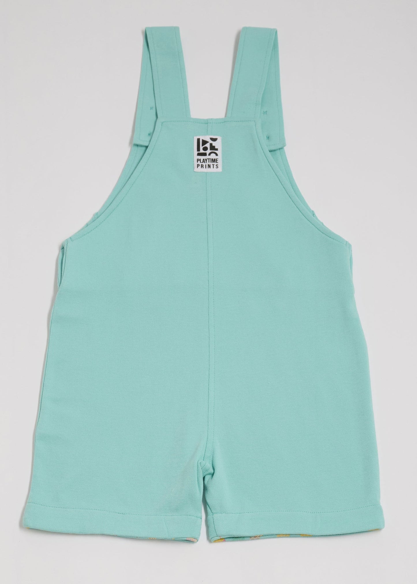 Back of turquoise short dungarees with Playtime Prints brand label.