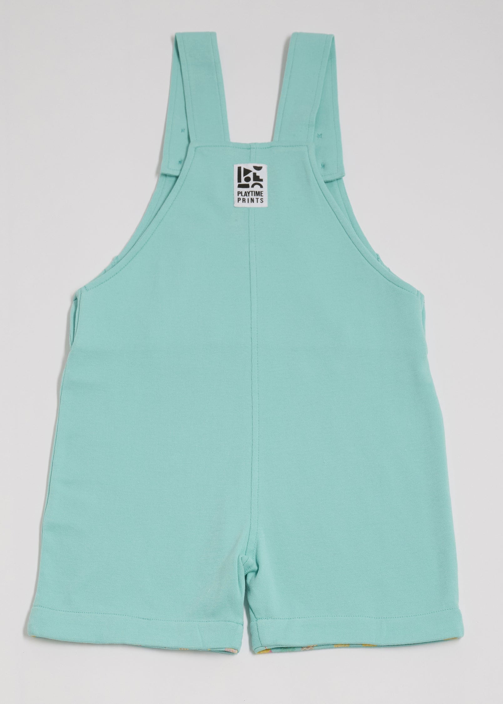 Back of turquoise short dungarees with Playtime Prints brand label.