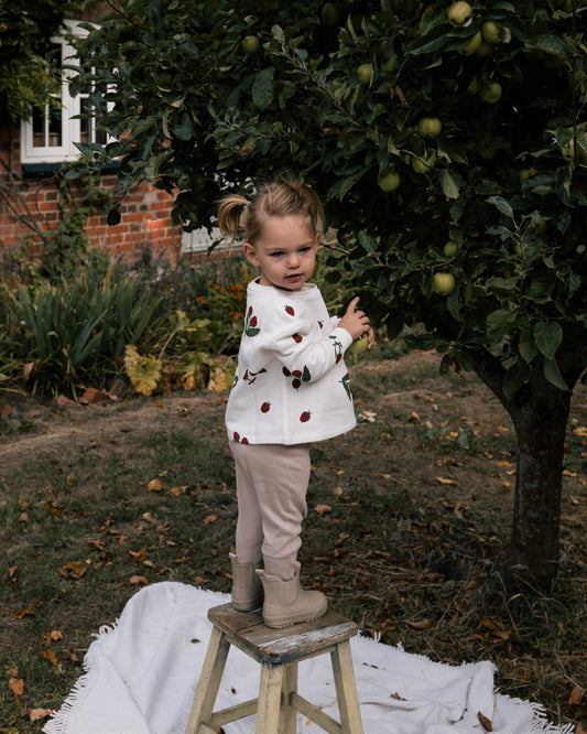 Toddler wearing Wildgreen raspberry print sweater made from organic cotton whilst apple-picking, unisex and gender-neutral sustainable kidswear